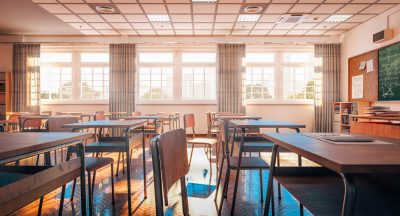 interior of a traditional school classroom with wooden floor and furniture.