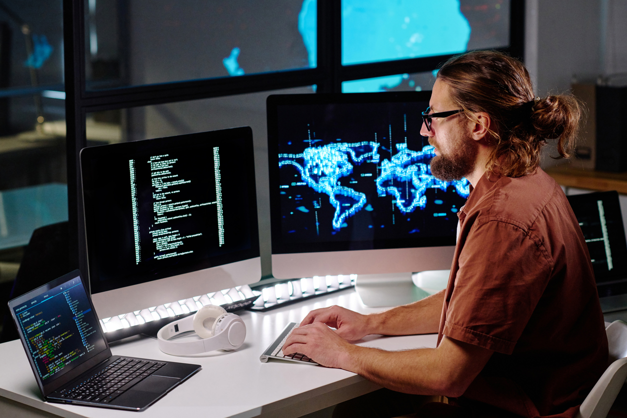 Young male programmer in eyeglasses looking at coded data on computer screen