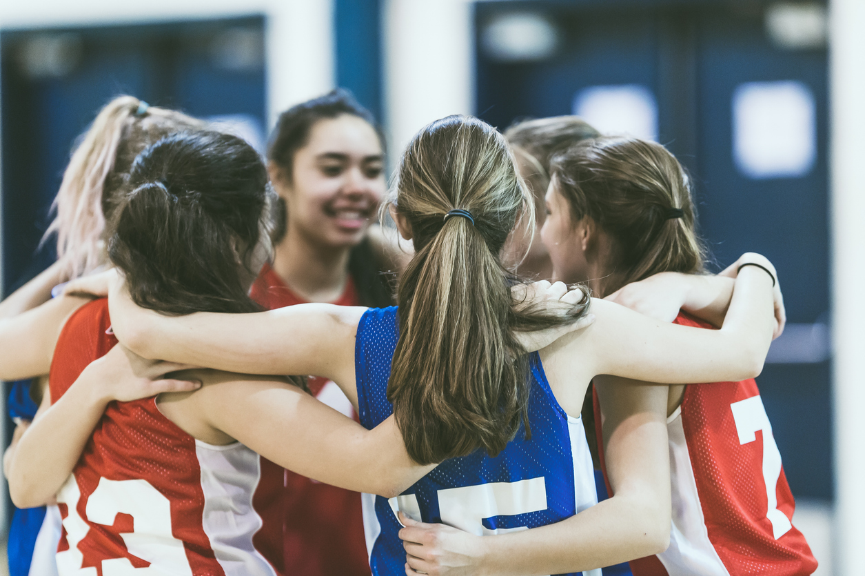 Group of female high school basketball players encouraging one another